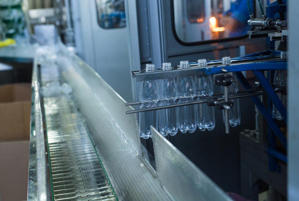Plastic water bottles on conveyor and water bottling machine industry Machingo