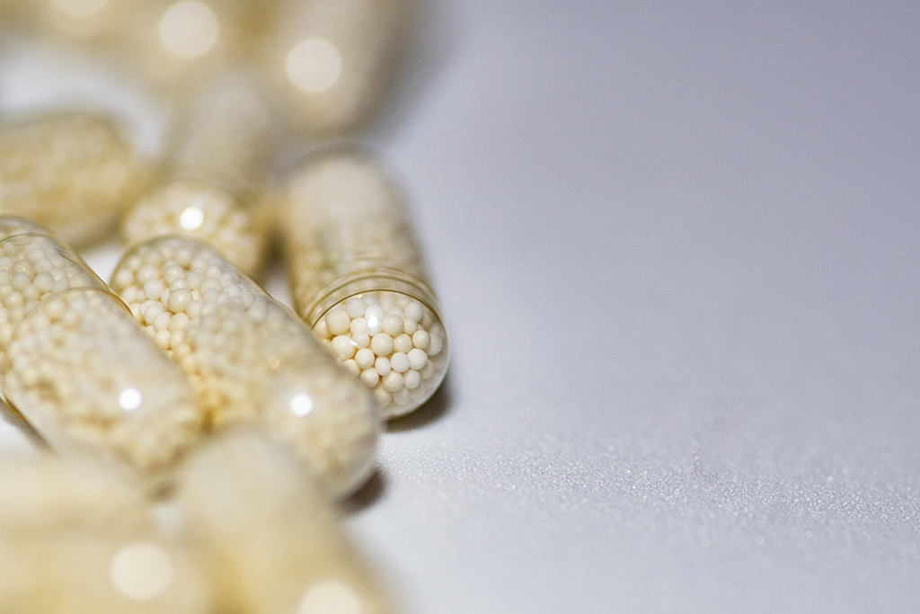 Selective focus shot of capsules pm a white surface - Machingo