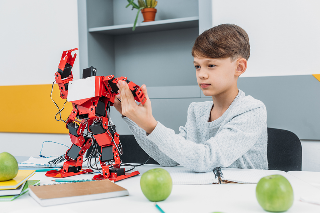 attentive boy working with a robot at STEM robotics lesson Machingo