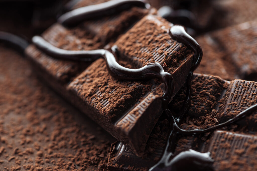 Close up view of pieces of dark chocolate bar with liquid chocol Machingo