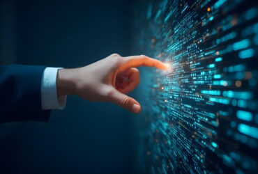 Businessperson's hand in a suit reaches toward a glowing wall of code in a high-tech display.
