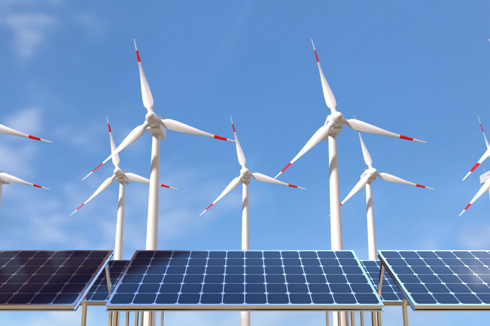 Solar panels in the foreground with wind turbines in the background under a clear blue sky