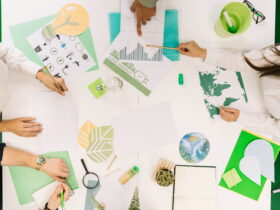 Top-down view of people around a white table working on environmental charts and illustrations.