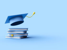 Blue graduation cap perched on a stack of textbooks against a blue backdrop, symbolizing education and achievement.
