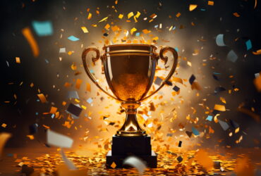 Golden trophy on a pedestal with orange and teal confetti falling around it.