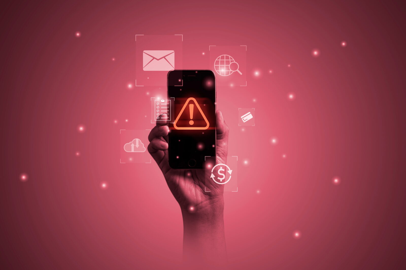 Hand holding a smartphone with an orange warning triangle on the screen, surrounded by floating digital icons against a pink gradient background.