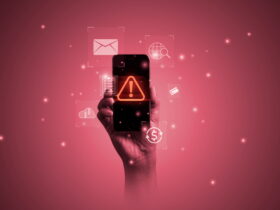 Hand holding a smartphone with an orange warning triangle on the screen, surrounded by floating digital icons against a pink gradient background.