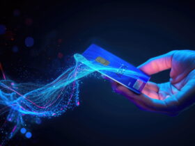 A hand holds a blue credit card with a visible chip against a dark, neon-lit background.