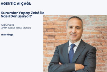 Tuğrul Cora, UiPath Türkiye Genel Müdürü, brick duvar önünde takım elbisesiyle gülümser bir portre.